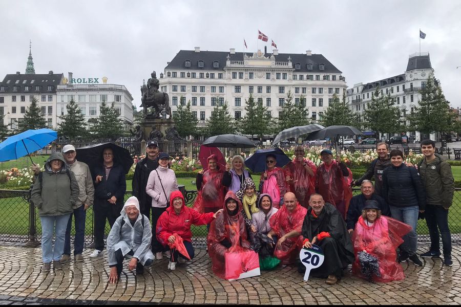 Un grupo con chubasqueros posa bajo la lluvia en la plaza Kongens Nytorv de Copenhague