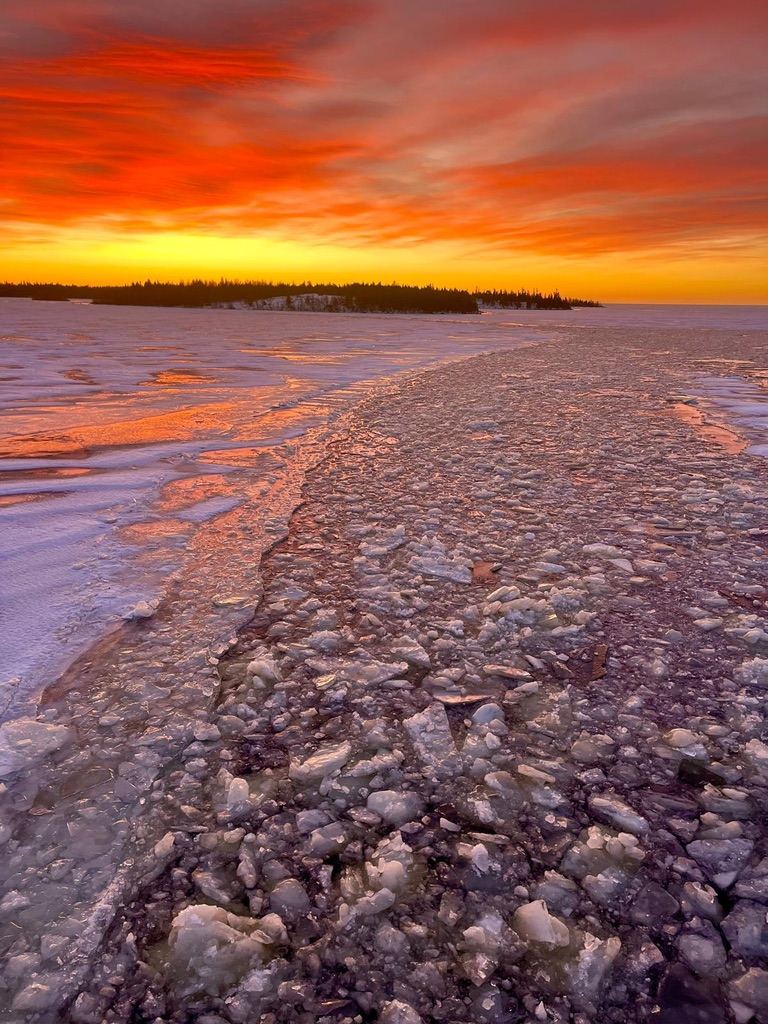 Amanecer naranja sobre las placas de hielo de un lago del norte