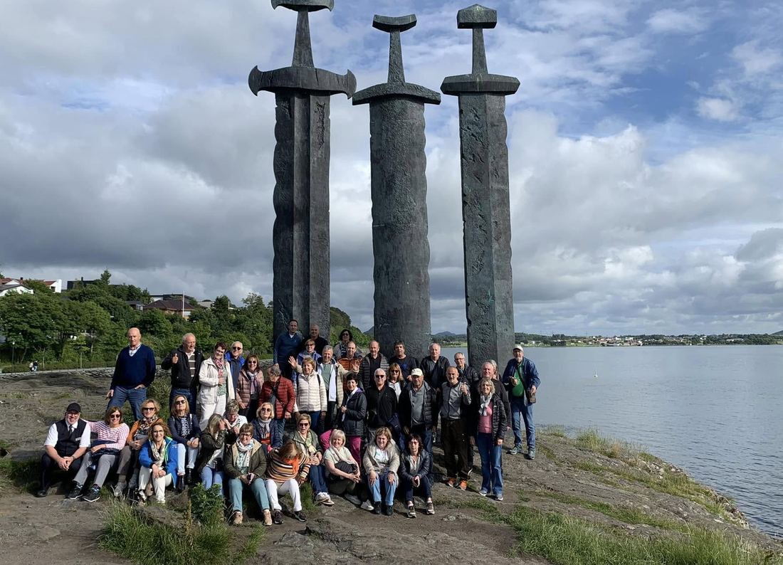 El grupo completo posa ante el monumento de las espadas en la roca, en Stavanger