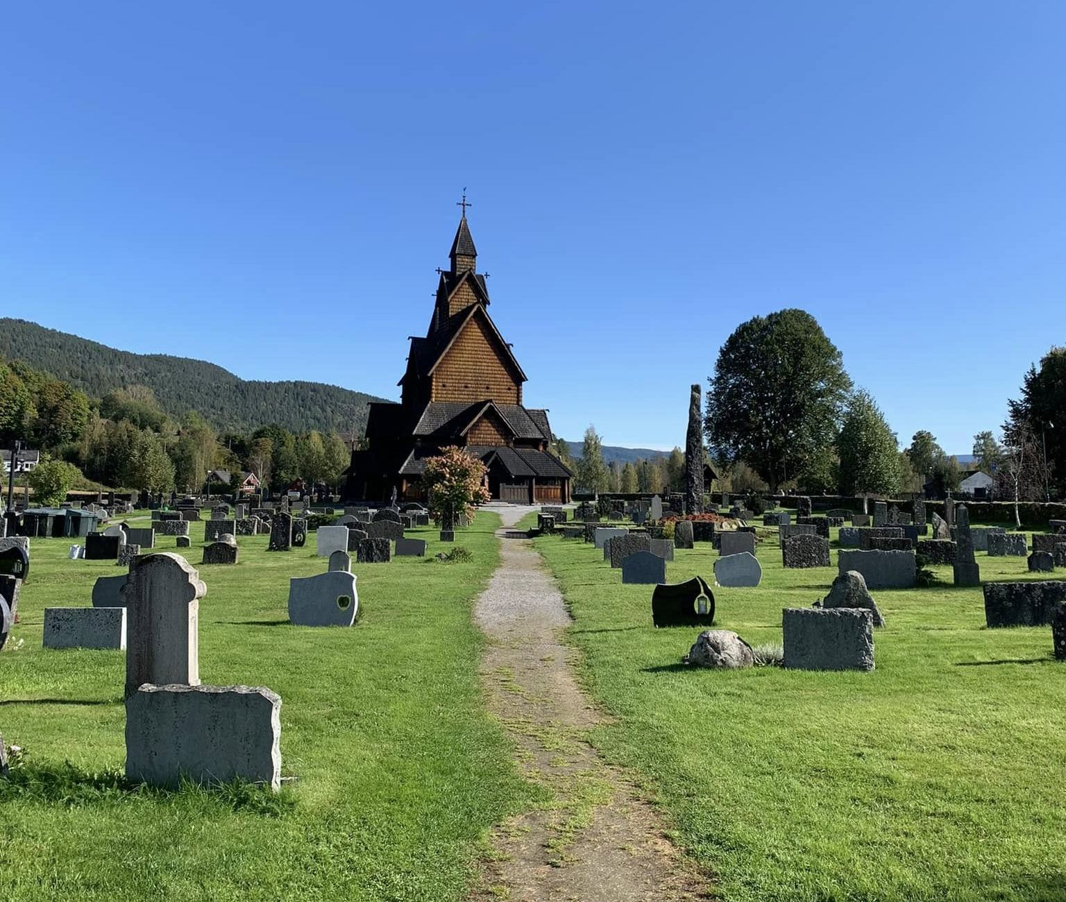 Iglesia de madera noruega al final de un sendero entre l&aacute;pidas